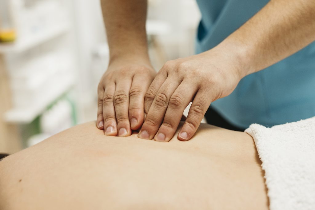 Manos de fisioterapeuta tratando la espalda de un paciente